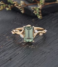 an emerald colored stone surrounded by white diamonds on a wooden surface with greenery in the background