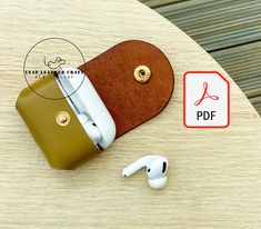 a pair of ear buds sitting on top of a wooden table next to a leather case