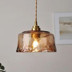 a glass light hanging from a ceiling in a room with pictures on the wall behind it