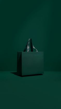 a white bag sitting on top of a green floor in front of a black wall