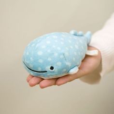 a hand holding a blue stuffed whale with white polka dots on it's body