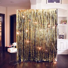 a gold curtain with lights hanging from it's side in a room filled with furniture