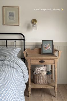 a small wooden table sitting next to a bed in a room with white walls and wood flooring