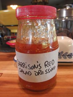 a jar filled with red liquid sitting on top of a wooden table next to a stove