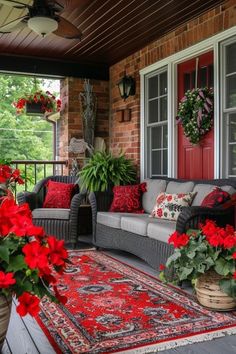 a porch with red flowers and potted plants on the front steps, along with an area rug