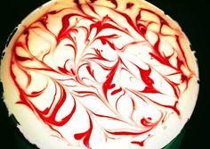 a cake with red swirls on it sitting on a green platter in front of a black background