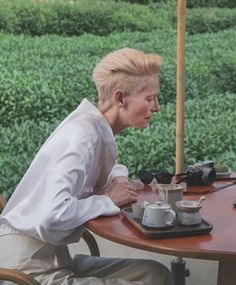 an older woman sitting at a table outside