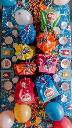 a table topped with lots of colorful balloons and plates covered in paper wrapped around them