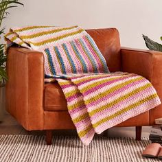 a couch with a blanket on top of it next to a potted plant and books