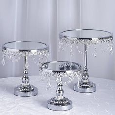 two silver candlesticks sitting on top of a white table cloth covered tablecloth