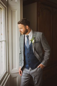 a man in a suit and tie standing by a window