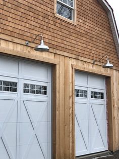 two white garage doors are open in front of a brown building with a light on the side