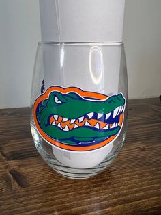 a glass with an alligator's head on it sitting on top of a wooden table