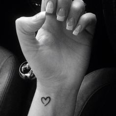 a woman's hand with a small heart tattoo on it