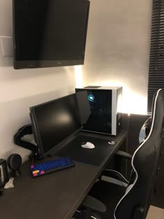 a computer desk with two monitors and a keyboard on it in front of a flat screen tv