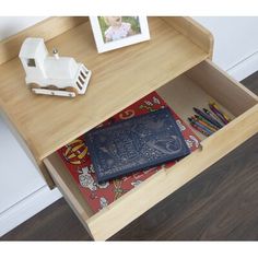 an open drawer with a book on it next to a photo and some crayons