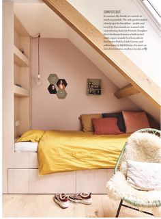 an attic bedroom with yellow bedding and wooden flooring is featured in the magazine