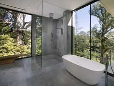 a bathroom with large windows and a bathtub in the middle, overlooking trees outside