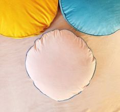 three round pillows sitting on top of a bed next to each other in different colors