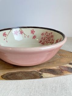 a pink and white bowl sitting on top of a cutting board next to a knife