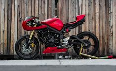 a red motorcycle parked next to a wooden fence