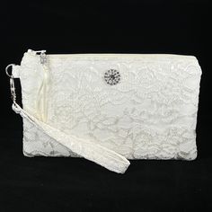 Bridal Ivory Wristlet Purse for the bride to be.  Designed to hold your essentials, this wristlet is small enough to carry easily, but big enough for all your needs!   This purse is made in Ivory Lace, and is suitable for a wedding, as a clutch for the bride, bridesmaid, or use with an evening formal.   Can also be used as a Makeup Bag, Phone Holder, or a Gift For The Bride. *Please note the Wristlet you receive will vary from the one pictured due to the cut of the fabric. The features of this wristlet include: ~ Handcrafted from ivory lace and cotton fabric. ~ Nylon zipper.  ~ Includes dazzling silver plated rhinestone button and a little bling on the zipper pull.  ~ Measures approx. 8 inches wide by 5 inches tall.  ~ Will hold larger phones.  ~ Detachable wrist strap on a metal lobster c Wristlet Purse, Wedding Bag, Evening Formal, Make Up Bag, Purse Clutch, Ivory Lace, Formal Wedding, Bride Gifts, Wrist Strap