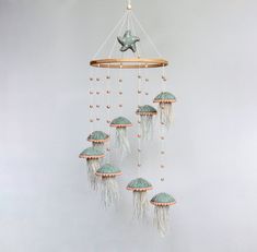 a wind chime hanging from the ceiling in front of a white wall with beads