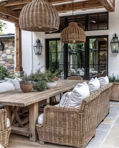 an outdoor dining area with wicker furniture and hanging lanterns on the ceiling, along with potted plants