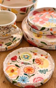 a table topped with plates and cups on top of a wooden table covered in flowers