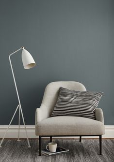 a living room with a chair, lamp and coffee cup on the floor in front of it