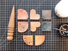 several different shapes and sizes of wooden objects on a table with paintbrushes next to them