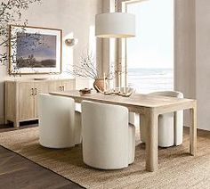 a dining room table with white chairs and a vase on top of it in front of a large window