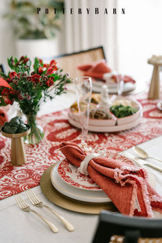 the table is set with red and white plates, silverware, and napkins