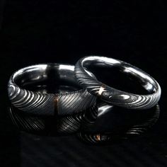 The men's ring is 6mm wide with a 1 millimeter vertical 14k rose gold inlay and the women's ring is 4mm wide with a 1 millimeter 14k rose gold inlay. Each ring is made to order by some of the best jewelry artisans that the industry has to offer. Our Damascus steel rings have an inside comfort fit to ensure that the ring will rest comfortably on your finger throughout the day and fits perfectly. This uniquely styled ring also has a two-tone finish with a light acid etch giving it the perfect soph Black Titanium Anniversary Rings, Black Stainless Steel Promise Ring, Minimalist Black Couple Rings For Anniversary, Black Stainless Steel Couple Rings For Promise, Black Titanium Jewelry With Polished Finish, Black Elegant Engraved Promise Ring, Damascus Wedding Band, Damascus Steel Ring, Wide Ring