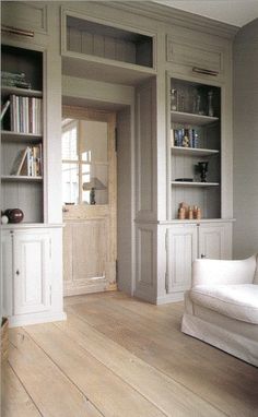 a living room with white furniture and book shelves on either side of the couch,