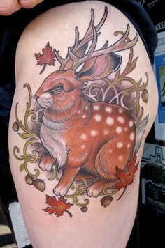 a deer tattoo on the thigh with autumn leaves around it and an antelope