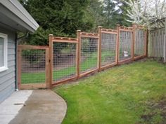 a fence that is next to a house with grass and trees in the back ground