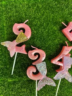 three pink flamingo cake toppers sitting on green grass in the shape of numbers