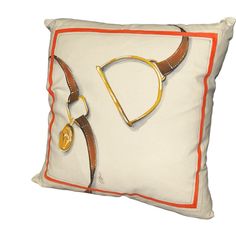 a white pillow with brown and orange trimmings on it's side, featuring a horse bit