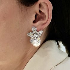 a close up of a woman's ear wearing earrings with flowers and pearls on them