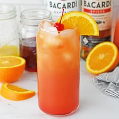 an orange drink with a cherry garnish on the rim and surrounded by other drinks