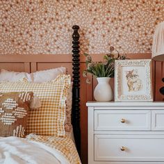 a bedroom with a bed, dresser and lamp on top of the night stand in front of it