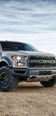 a silver truck parked on top of a dirt field