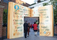 two people are walking through an open book like structure with words written on the sides