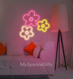 a white couch sitting under a neon flower sign