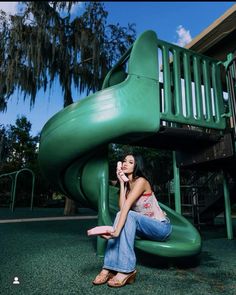 a woman sitting on top of a green slide