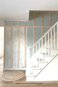 an empty room with white walls and wood trimming on the wall, next to a stair case