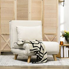 a white chair with a black and white blanket on it in front of a wooden paneled wall