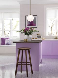 a kitchen with purple cabinets and stools next to a counter top that has flowers on it