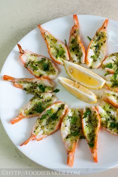 a white plate topped with shrimp and lemon wedges